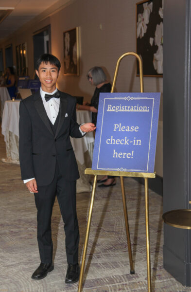BlindnessGala3-CedarHill-21 a young man in a tux standing at a check-in sign at the Night for Sight Gala 2024
